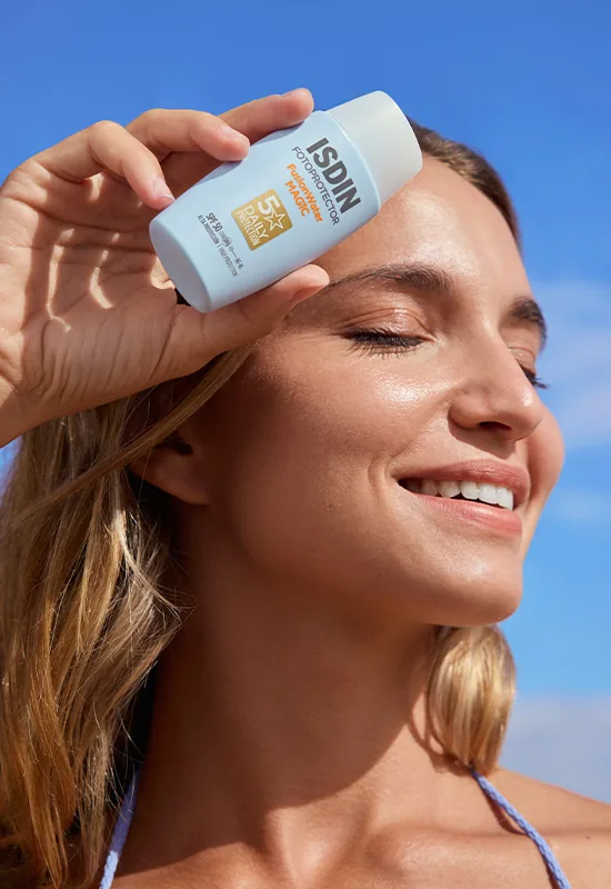 Une femme applique son photoprotecteur ISDIN, le visage tourné vers le soleil