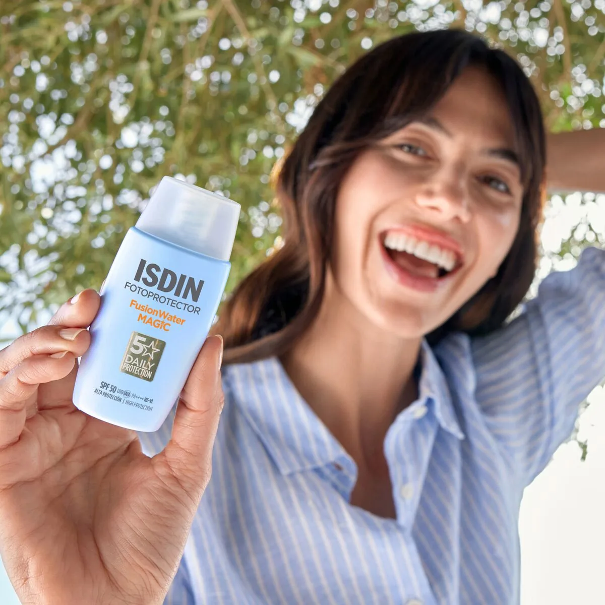 Une femme sourit en tenant son photoprotecteur Fusion Water Magic ISDIN